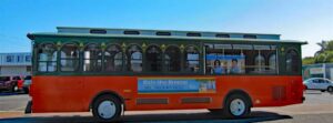 Free Siesta Key Breeze trolley driving through Siesta Key village with passengers enjoying convenient island transportation