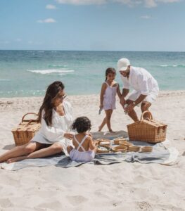 Family enjoying a beach picnic with two young children on a sunny day at Siesta Key