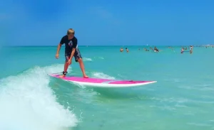 Young boy paddleboarding on gentle waves at Siesta Key Beach