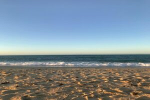 Golden sand and gentle waves on Siesta Key Beach under a clear blue sky at sunset