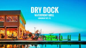 Dry Dock Waterfront Grill in Longboat Key, Florida, featuring waterfront dining at sunset with string lights, a dockside patio, and glowing reflections on Sarasota Bay.