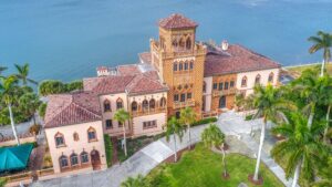 Aerial view of the Ca’ d’Zan mansion in Sarasota, Florida, featuring Venetian Gothic architecture, red-tiled roof, and ornate tower overlooking Sarasota Bay.