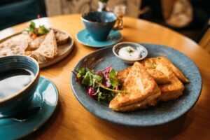 A gourmet brunch plate with golden toast, fresh greens, and cream sauce served with coffee at a Siesta Key café.