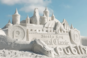 Detailed sand sculpture of a castle and dragon with “Siesta Key Crystal Classic” carved into the sand on Siesta Beach.