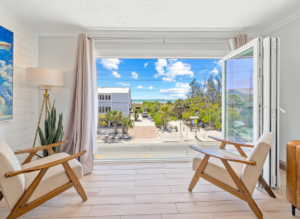 Cozy seating area with ocean view Two chairs by a large window overlooking palm trees and a view of the beach and ocean under a sunny sky