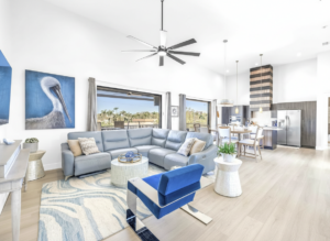 Spacious living room and kitchen Bright open living space with sectional sofa, high ceilings, modern kitchen, and large sliding doors leading to a balcony
