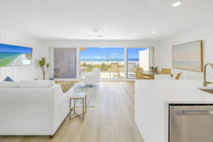 Bright oceanview penthouse in Siesta Key with modern living space, floor-to-ceiling windows, and private balcony overlooking the beach