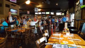 Customers dining and watching sports inside Captain Curt’s Crab & Oyster Bar in Siesta Key, featuring TVs, casual seating, and a lively game day atmosphere.