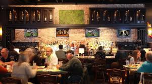 Guests dining inside Gecko’s Grill & Pub with TVs showing sports, warm lighting, bar seating, and a relaxed pub atmosphere near Siesta Key.