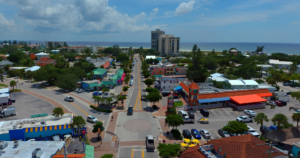 Aerial view of Siesta Key Village with colorful restaurants, shops, streets, and the Gulf of Mexico in the background.